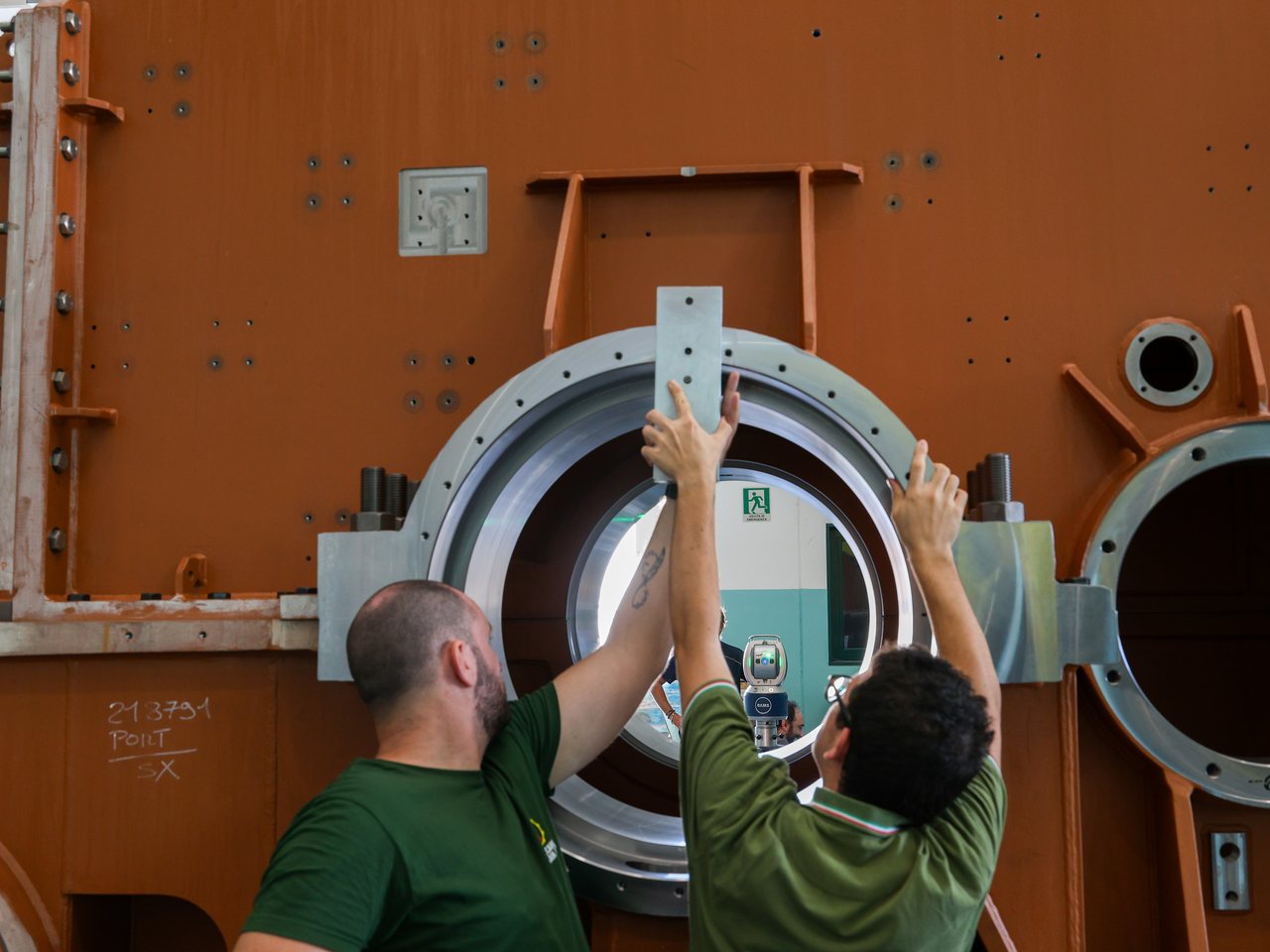 Due operatori sull'alesaggio di un corpo, con il laser tracker in asse oltre il foro
